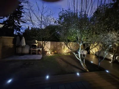 Jardin avec terrasse bois et éclairage LED de nuit, ambiance cosy.