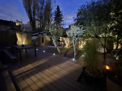 Jardin avec terrasse bois et éclairage LED de nuit, ambiance cosy.