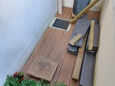 Terrasse en construction avec lames de bois posées et outils à côté.