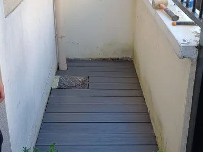Terrasse terminée avec lames composites gris foncé et petit regard intégré.