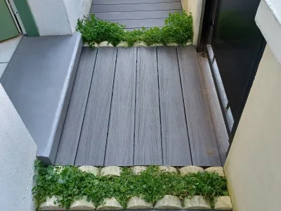 Petite terrasse avec lames grises et marche d’accès, entourée de végétation