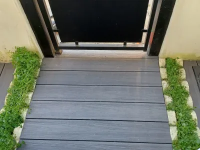 Terrasse en bois composite gris avec jardinière et portail noir