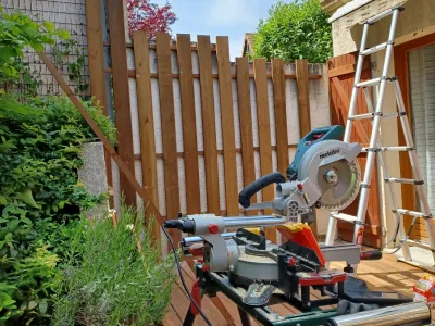 Pose d’une clôture en bois avec outils de chantier visibles dans un jardin en cours d’aménagement