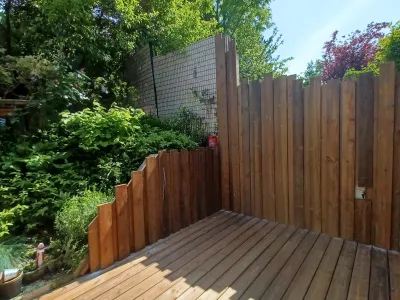 Clôture en bois et terrasse bois installées dans un jardin paysager