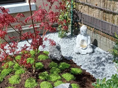 Aménagement de jardin zen avec statue décorative, gravier blanc et plantations structurées