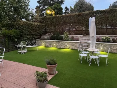 Coin détente extérieur avec pelouse verte, tables et chaises, éclairage nocturne