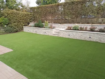 Pelouse synthétique posée dans un jardin avec muret et plantations décoratives