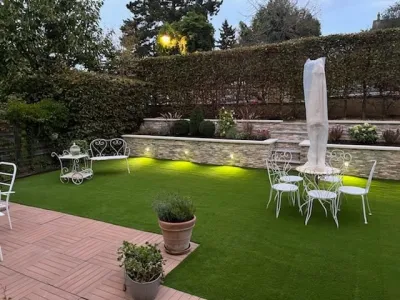 Jardin paysager de nuit avec pelouse synthétique, éclairage et mobilier extérieur