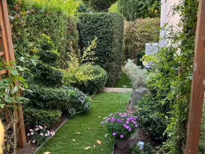 Petit jardin aménagé avec pelouse, massifs fleuris et haies taillées