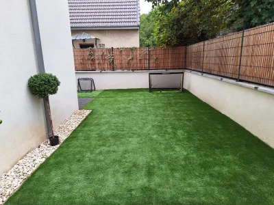 Pelouse synthétique installée dans un jardin étroit avec clôture et brise-vue