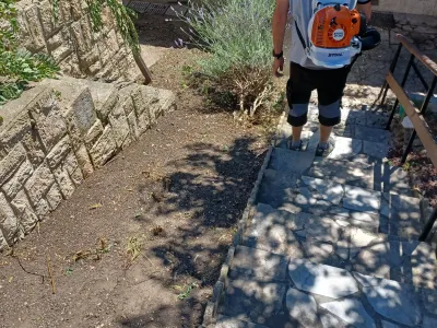 Paysagiste nettoyant des marches et un chemin extérieur dans un jardin
