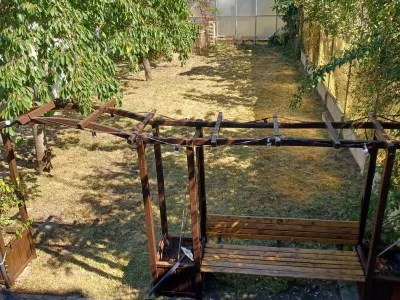 Pergola en bois avec balançoire installée dans un jardin ensoleillé.