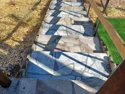 Escalier en pierre avec marches bordées de paillage et pelouse artificielle