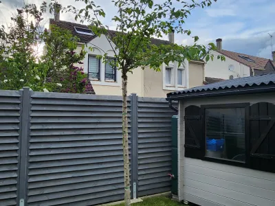 Clôture moderne avec panneaux horizontaux et aménagement paysager devant une maison