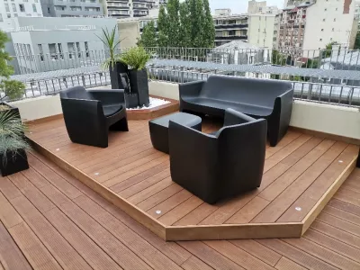 Espace détente sur terrasse en bois avec canapé et fauteuils noirs modernes