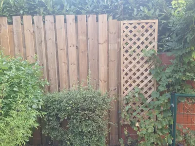 Palissade en bois avec treillis pour végétation, coin du jardin aménagé.