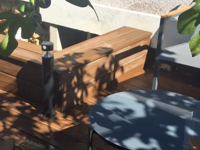 Détail de terrasse en bois avec banc intégré et mobilier de jardin.