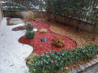 Aménagement paysager avec gravier blanc, paillis rouge et plantes décoratives