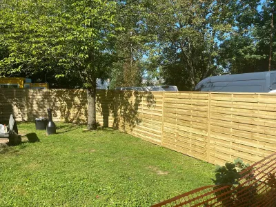 Travaux d’aménagement extérieur avec pelouse et clôture en bois récemment installée