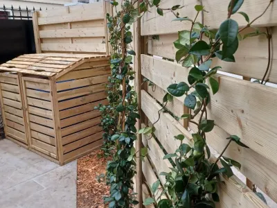 Composteurs en bois installés dans un coin de terrasse avec treillis