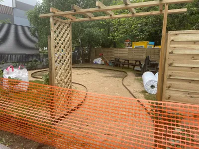 Aire de jeux en bois en cours de montage avec filet de sécurité orange autour