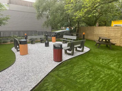 Vue rapprochée de l’allée en gravier avec mobilier urbain et pelouse artificielle
