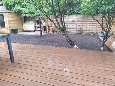 Terrasse en bois composite fraîchement posée avec arbres conservés dans le jardin
