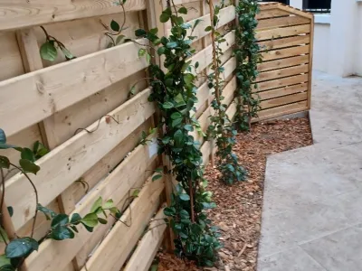 Clôture en bois avec treillis et plantes grimpantes sur le côté d’un chemin