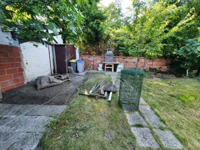 Jardin avant travaux avec sol brut, végétation existante et zone à réaménager