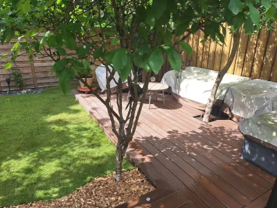 Terrasse en bois aménagée autour d’un arbre avec espace détente au jardin