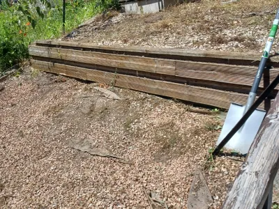 Mur de soutènement en bois en cours d’aménagement dans un jardin en pente