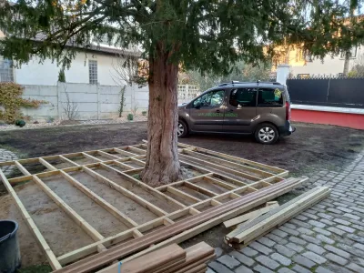 Structure en bois pour terrasse en construction autour d’un arbre, sol pavé