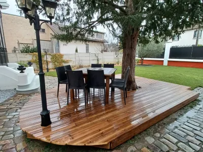Terrasse en bois terminée avec table et chaises, espace vert et lampadaire