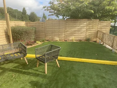 Espace détente avec pelouse synthétique, fauteuils extérieurs et clôture en bois