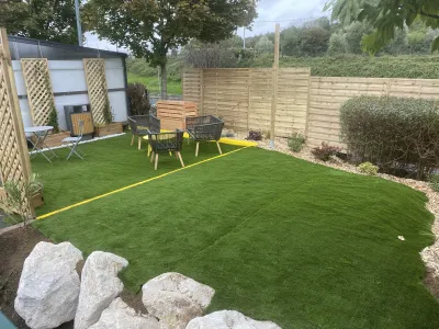 Jardin aménagé avec pelouse synthétique, salon de jardin et brise-vue en bois