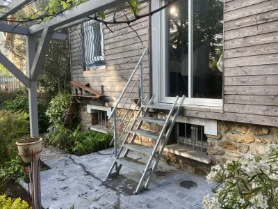 Escalier métallique extérieur menant à une terrasse en bois, entouré de végétation
