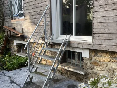 Escalier métallique extérieur menant à une terrasse bois, jardin.