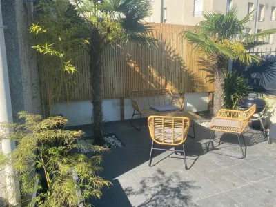 Patio extérieur avec mobilier en rotin et végétation, sol en gravier.