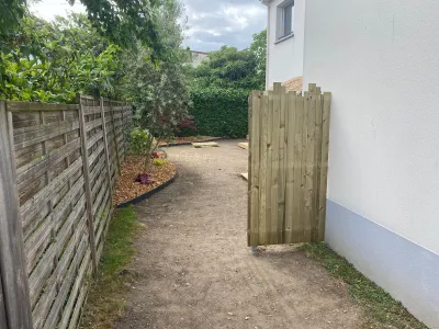 Chemin en terre entre deux clôtures bois, accès au jardin.