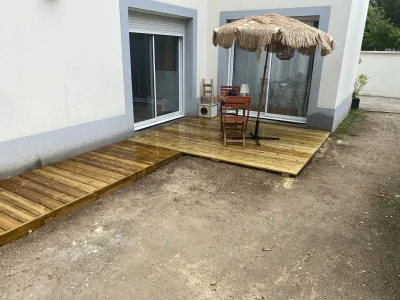 Terrasse bois en cours de finition le long de la maison, parasol fermé.