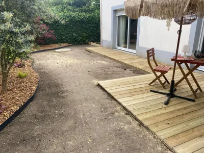 Terrasse bois installée avec table et chaises, sol préparé autour pour aménagement futur.