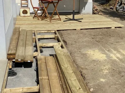 Terrasse bois partiellement posée avec sol en terre, zone prête pour extension.