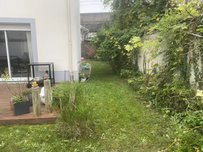 Jardin avec pelouse existante et plantes le long du mur, préparation pour aménagement.
