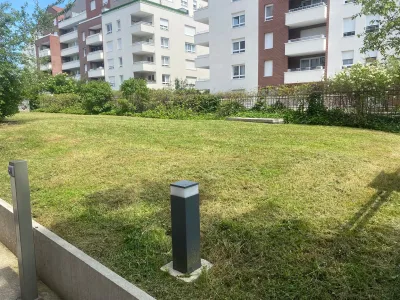 Grand espace vert avec pelouse tondue et bâtiments résidentiels en arrière-plan