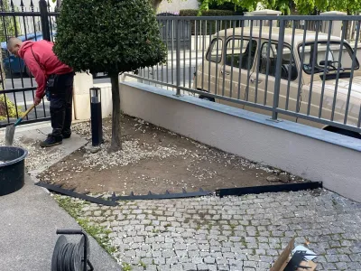 Ouvrier en train de poser du gravier sur un parterre bordé d’une allée pavée
