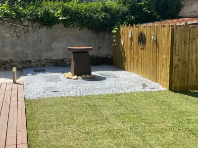 Aménagement extérieur avec clôture en bois, espace gravier et brasero central