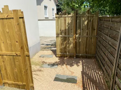 Portillon et clôture en bois installés le long d’une allée extérieure avec pas japonais et gravier décoratif
