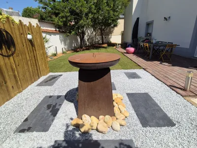 Terrasse avec plateau décoratif en métal entouré de gravier et de dalles noires