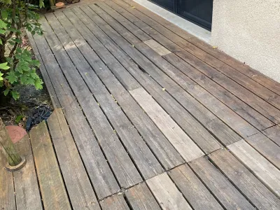 Ancienne terrasse en bois avant rénovation, lames usées le long d’une façade