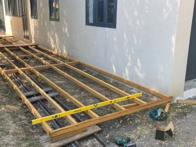 Structure de terrasse en bois en cours de pose avec lambourdes et niveau